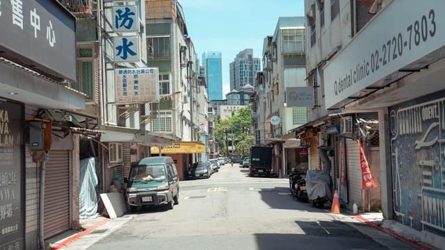 A typical street scene in Taipei, featuring local shops and a view of city buildings.