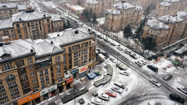 Aerial view of Qingdao's snow-covered residential buildings and streets in winter.