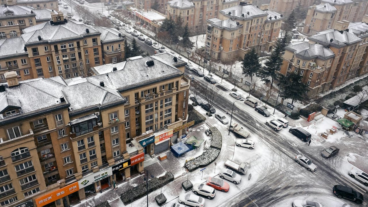 Aerial view of Qingdao's snow-covered residential buildings and streets in winter.