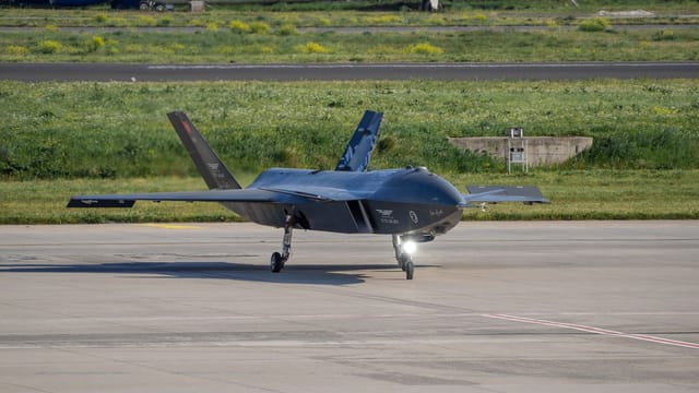 Turkish Baykar Bayraktar Kizilelma drone on a tarmac in Istanbul with aircraft in the background.