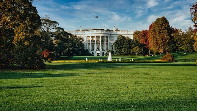 The White House with autumn foliage and a vast green lawn in Washington, D.C.
