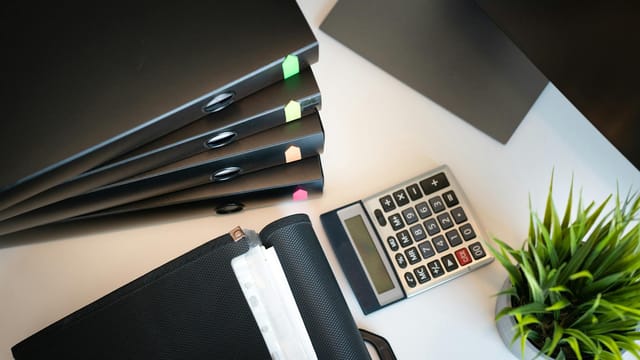 Top view of a tidy office desk with files, a calculator, and a plant, emphasizing organization.