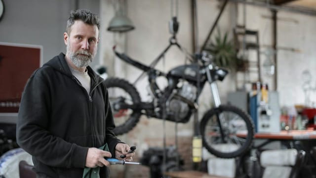 A skilled mechanic works with tools in a contemporary motorcycle repair shop.