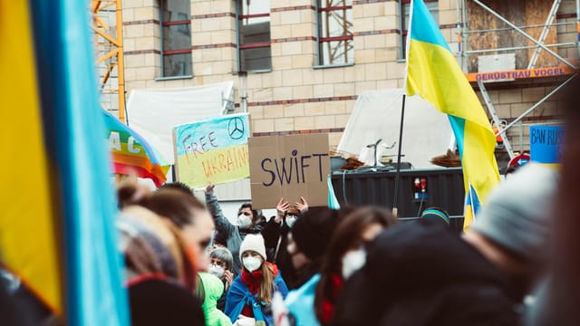 A large protest advocating for Ukraine with banners and flags, capturing public solidarity.