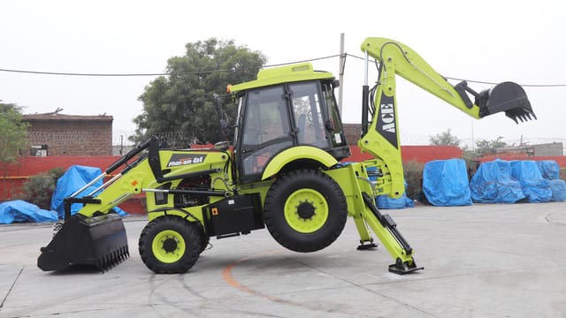 A vibrant ACE Phantom 4x4 backhoe loader is showcased in an outdoor setting in Faridabad, India.