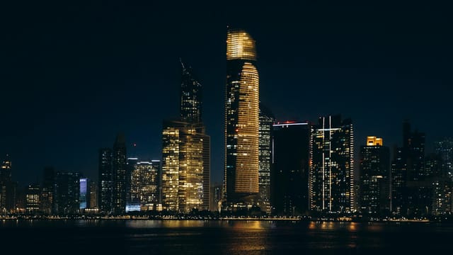 Stunning night view of Abu Dhabi's illuminated skyline reflecting on the water.