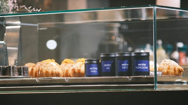 Delicious pastries and matcha tea neatly arranged in a sleek glass display case.