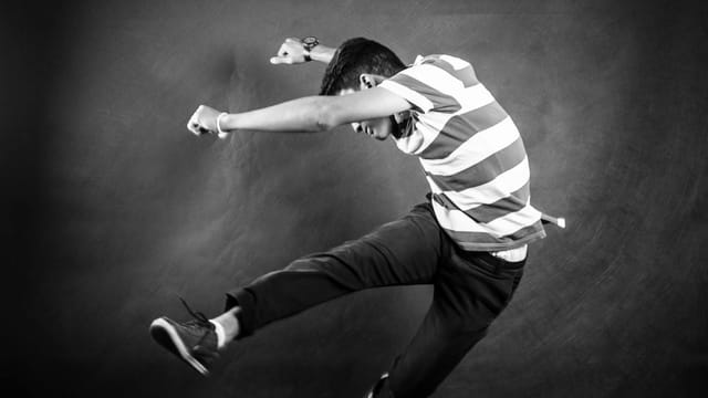 Black and white photo of a man in mid-air jump, showcasing energy and style.