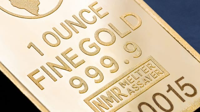 Detailed close-up of a 1 ounce fine gold bar with inscriptions, ideal for finance and investment themes.