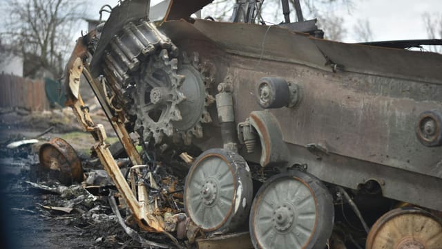 Close-up of a damaged military tank wreckage in an outdoor setting.