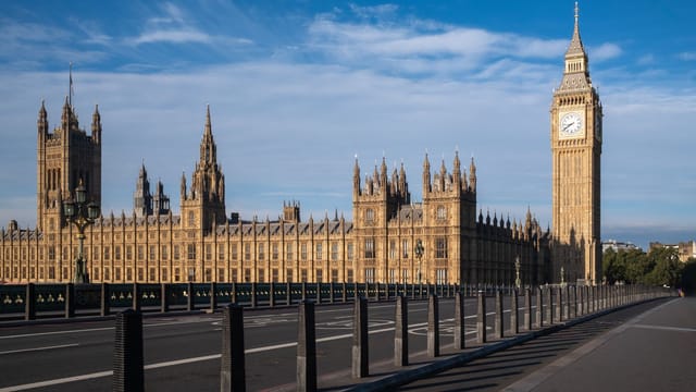 Iconic view of Big Ben and the Palace of Westminster in London, UK, under a blue sky.