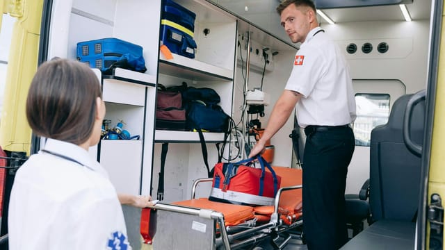 Two paramedics organizing medical supplies in an ambulance for emergency readiness.