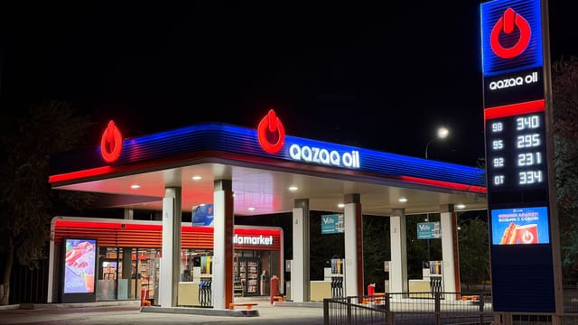 A brightly lit gas station at night featuring bold signage and illuminated fuel price display.