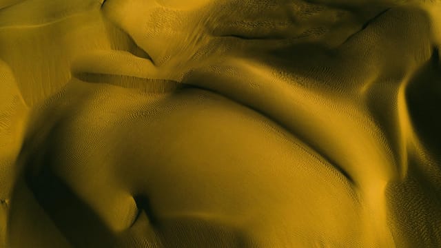 Stunning aerial view of golden sand dunes depicting natural patterns in Xinjiang, China.