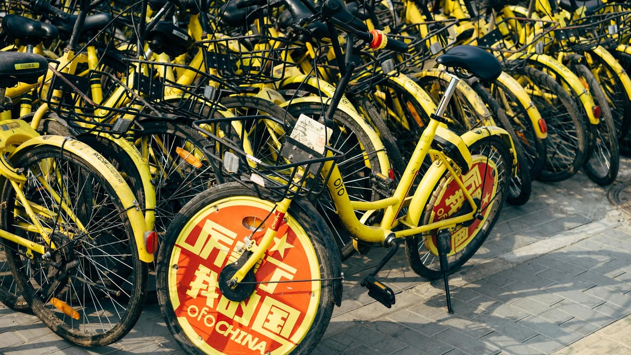 A fleet of yellow shared bicycles parked on a city sidewalk indicating urban mobility solutions.