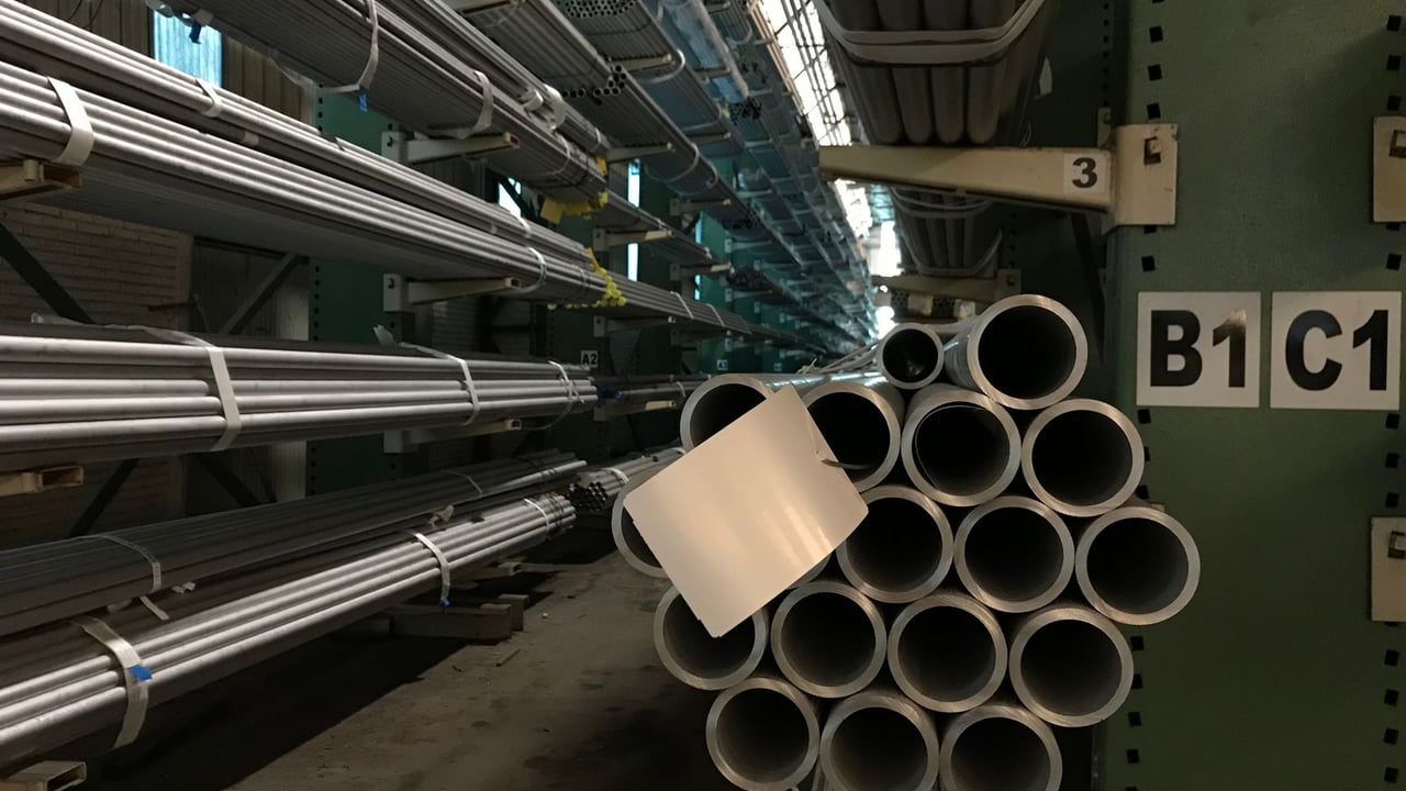 Rows of steel tubes stacked in an industrial warehouse, showcasing organized storage.