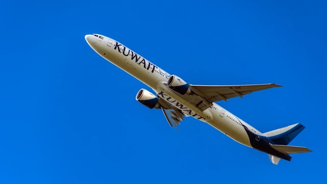 Kuwait Airways plane soaring against a vibrant blue sky, emphasizing aviation power.