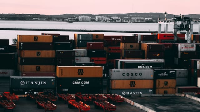 Illustrative image: A bustling container yard at a seaport with shipping containers stacked and ready for transport at twilight.