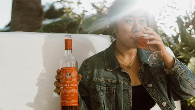 A woman savoring a glass of rosé wine in sunny outdoor setting, Portugal.
