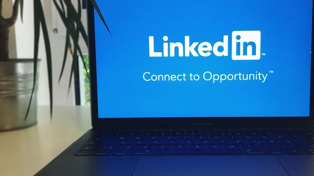 A laptop screen displaying the LinkedIn logo with the text 'Connect to Opportunity'.
