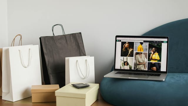 Laptop showcasing fashion e-commerce site alongside shopping bags, ideal for online shopping themes.