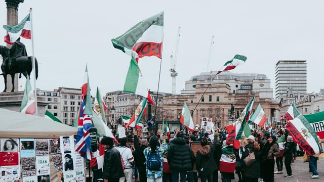 A vibrant protest in London with flags and signs expressing a strong message.