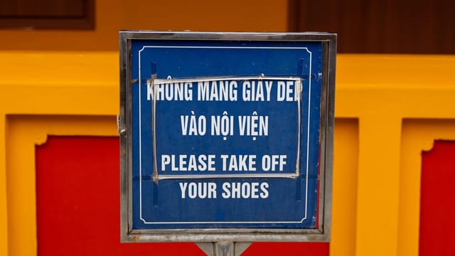 Close-up of bilingual sign in Hà Nội, Việt Nam, advising to remove shoes before entering.