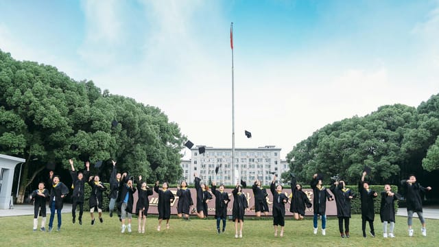 Group of students celebrating graduation by tossing caps into the air outdoors.
