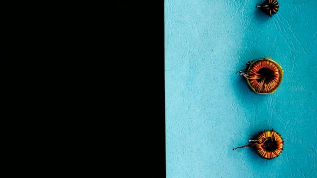 Top view of colorful electrical inductors on a vibrant two-tone background.