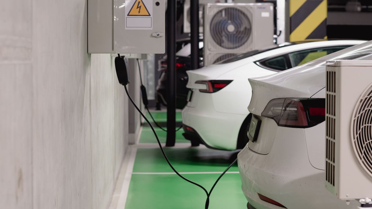 Illustrative image: Electric vehicles charging at an indoor station in a modern underground garage.