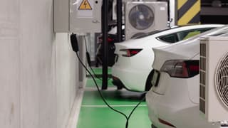 Illustrative image: Electric vehicles charging at an indoor station in a modern underground garage.
