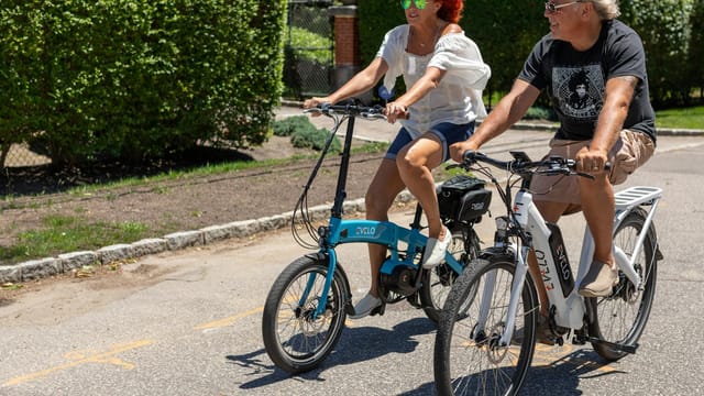 A couple rides electric bikes on a sunny day in Patchogue, NY.