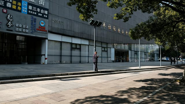 Street view of a businessman outside a modern building in urban China.