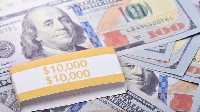 Close-up of $100 US dollar banknotes wrapped with a $10,000 band, symbolizing wealth and financial success.