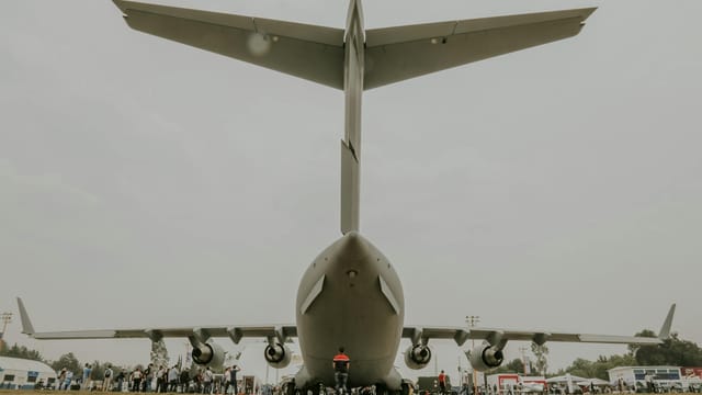 A striking rear view of a C-17 Globemaster jet with people observing at an air show.