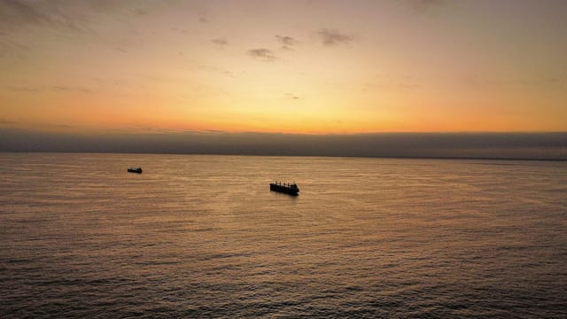 Aerial view of ships sailing on the Pacific Ocean during a beautiful sunset near Antofagasta, Chile.