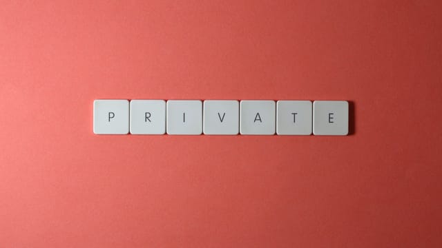 White letter tiles spelling 'PRIVATE' on a red background, offering conceptual minimalist design.