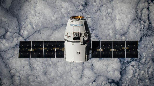 SpaceX Dragon spacecraft in orbit, highlighting advanced space technology with cloud backdrop.