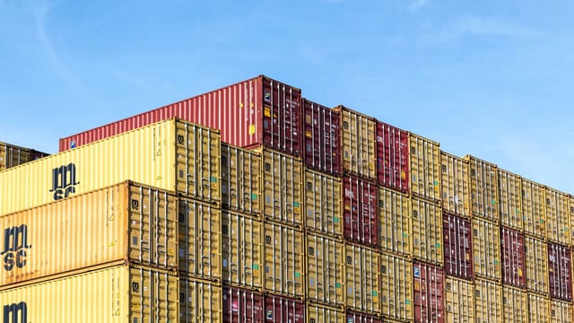 Illustrative image: Colorful stacked cargo containers in Hamburg port under a clear blue sky.