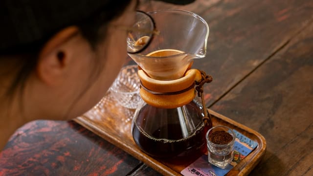 A person brewing artisan coffee with a Chemex in a Yunnan café, capturing the essence of craftsmanship.