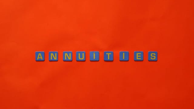 Conceptual image of the word 'Annuities' spelled with tiles on a vibrant red background.