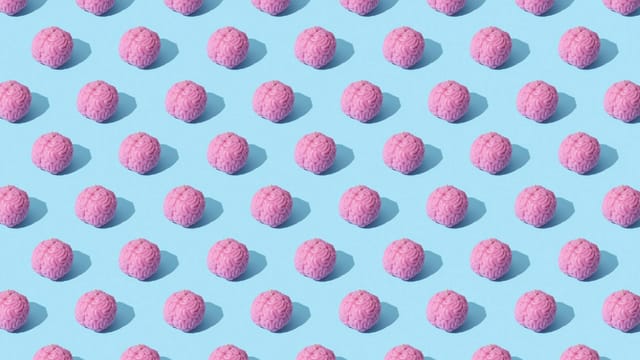 Creative composition of pink brain models in a repeating pattern on a light blue surface, showcasing abstract thinking.