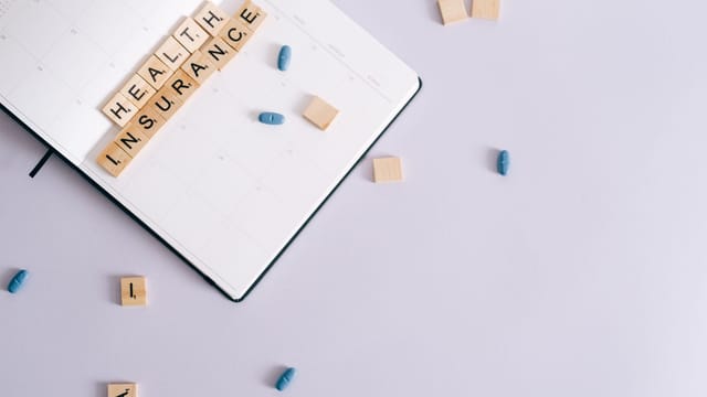 Flat lay of health insurance concept with planner and pills.