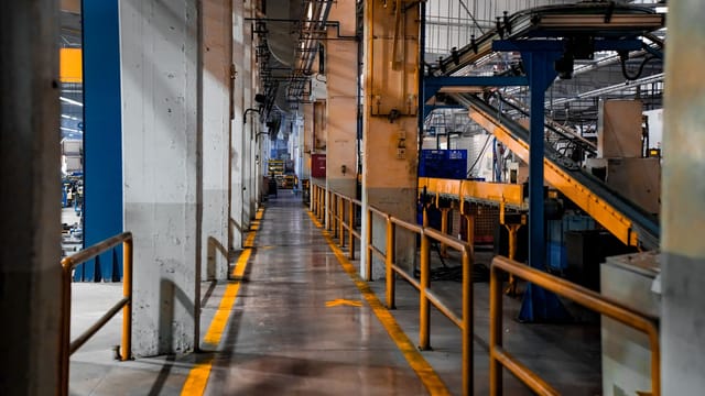 Inside view of an industrial factory featuring conveyor belts and empty walkways.