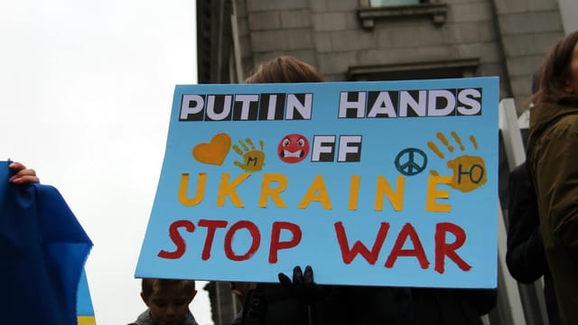 Protesters in Vancouver hold signs advocating peace and opposing war in Ukraine.