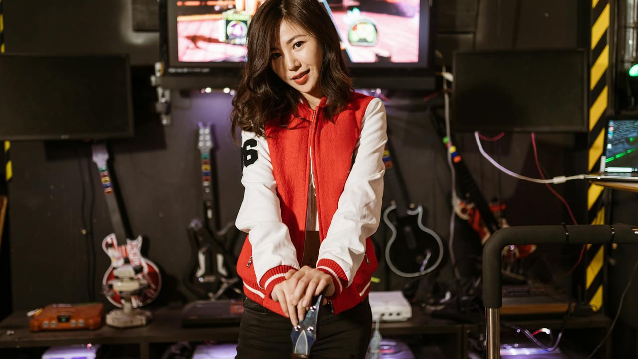 Young woman enjoying Guitar Hero session in a vibrant gaming lounge setting.
