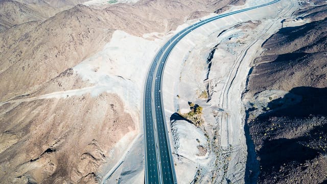 Aerial drone view of a road winding through the Al Gharbia desert landscape in Abu Dhabi.