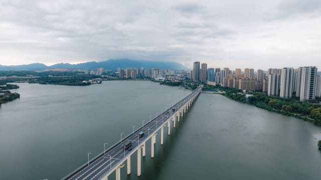 Stunning aerial shot of a bridge over water with Lu'an city skyline under cloudy skies.