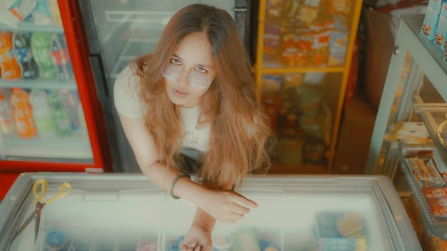Young woman stands at a fridge in an Indian retail store. Overhead view.