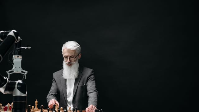 An elderly man competes against a robotic arm in a chess game, symbolizing the intersection of technology and strategy.
